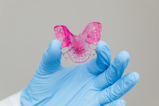 小矯正の装置を見せる歯科医師の手