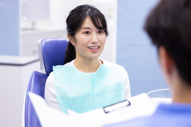 インビザライン矯正後の後戻りを歯科医院で相談する女性