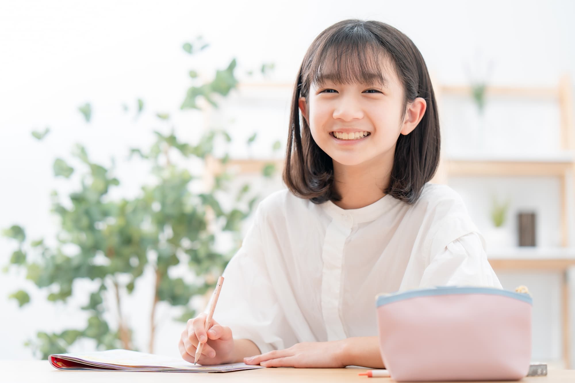 笑顔で勉強をしている綺麗に歯が生え変わった女の子