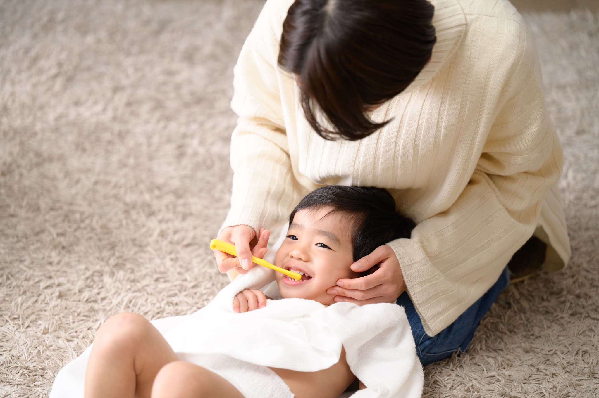 生え変わりの時期に虫歯にならないように子どもの歯の仕上げ磨きをする母親