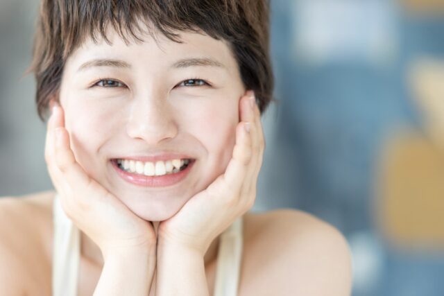 頬杖をついて笑う八重歯の女性