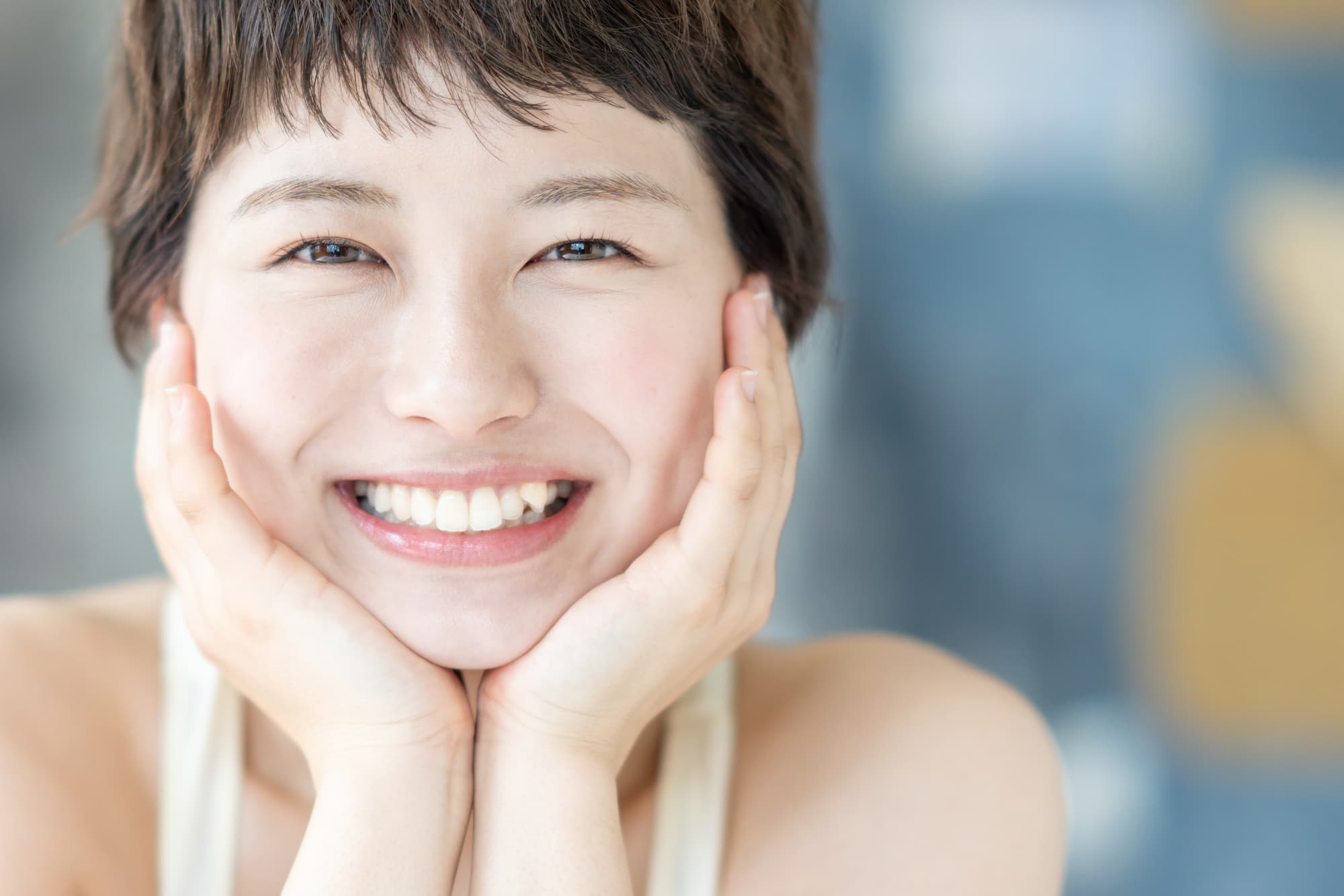頬杖をついて笑う八重歯の女性