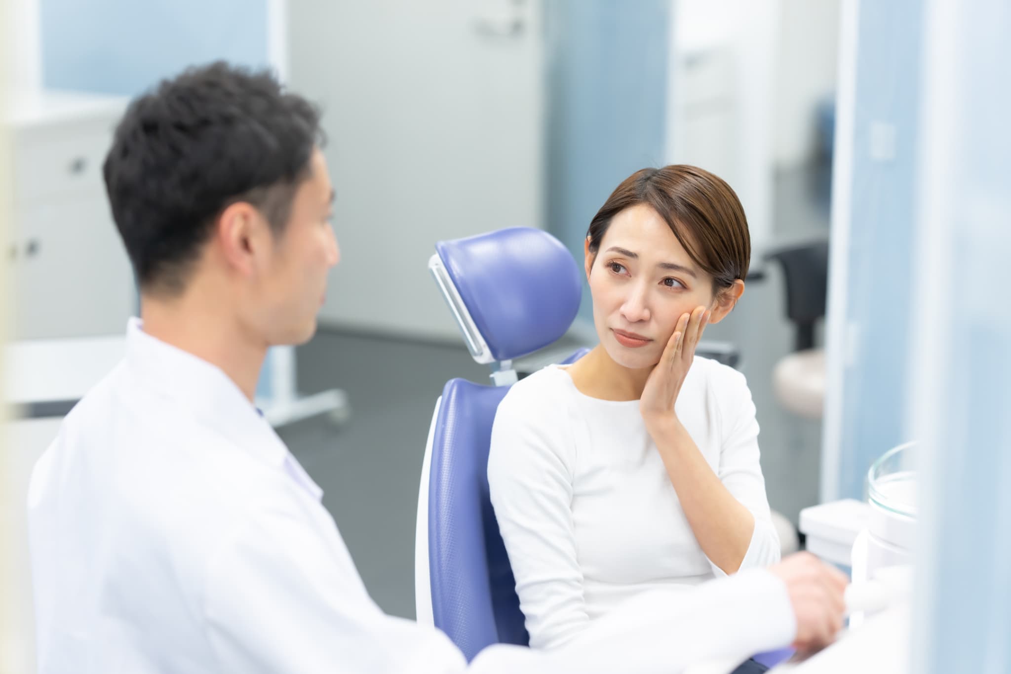 オフィスホワイトニング中に痛みを感じ歯科医師へ伝える女性
