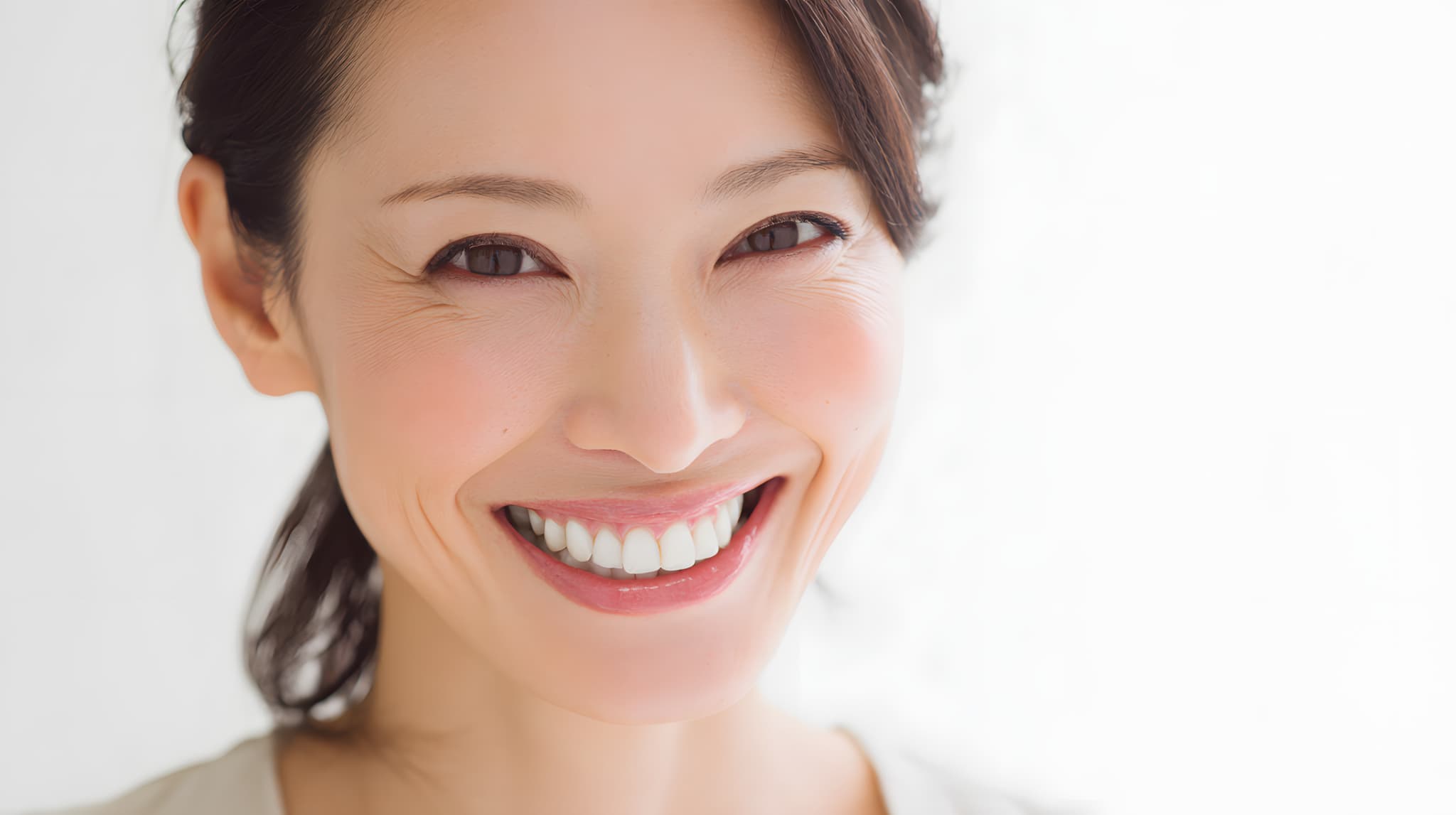 ホワイトニングで白くなった歯を見せて笑う女性